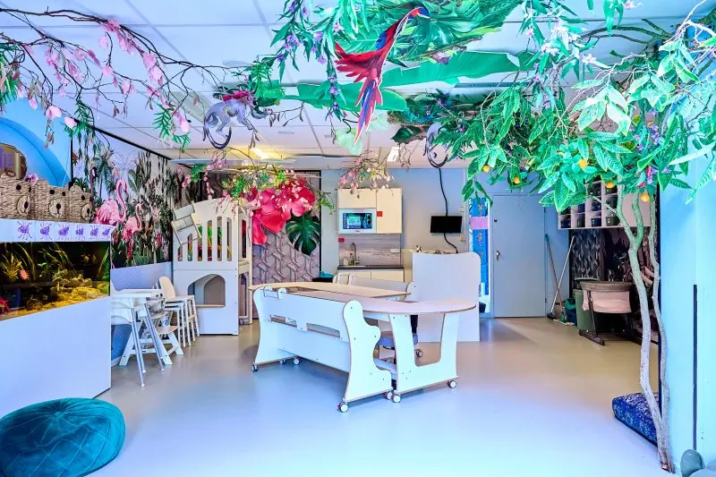 Groepsruimte met witte tafels en jungle