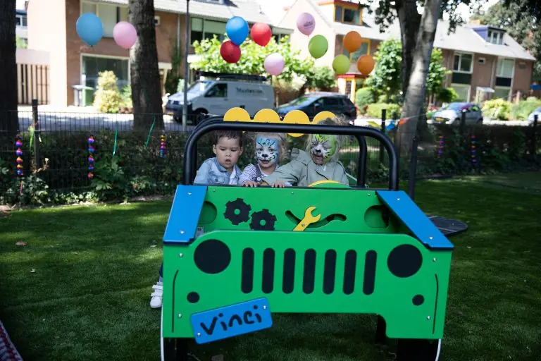 Kinderen in een speelgoedjeep op het gras